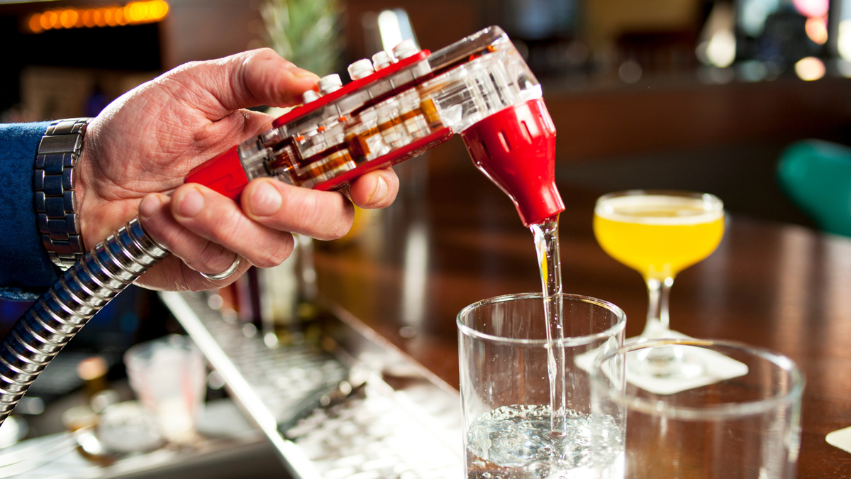 Bartender using a commercial soda gun bar gun to dispense a beverage at a bar